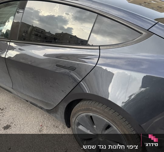 חלון צד אחורי של רכב כהה עם השתקפות שמיים